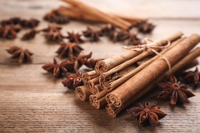 Aromatic cinnamon sticks and anise on wooden table, closeup