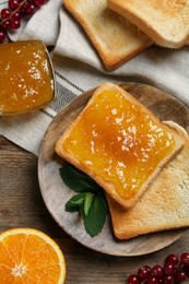 Photo of Delicious toasts served with jam, orange and berries on wooden table, flat lay