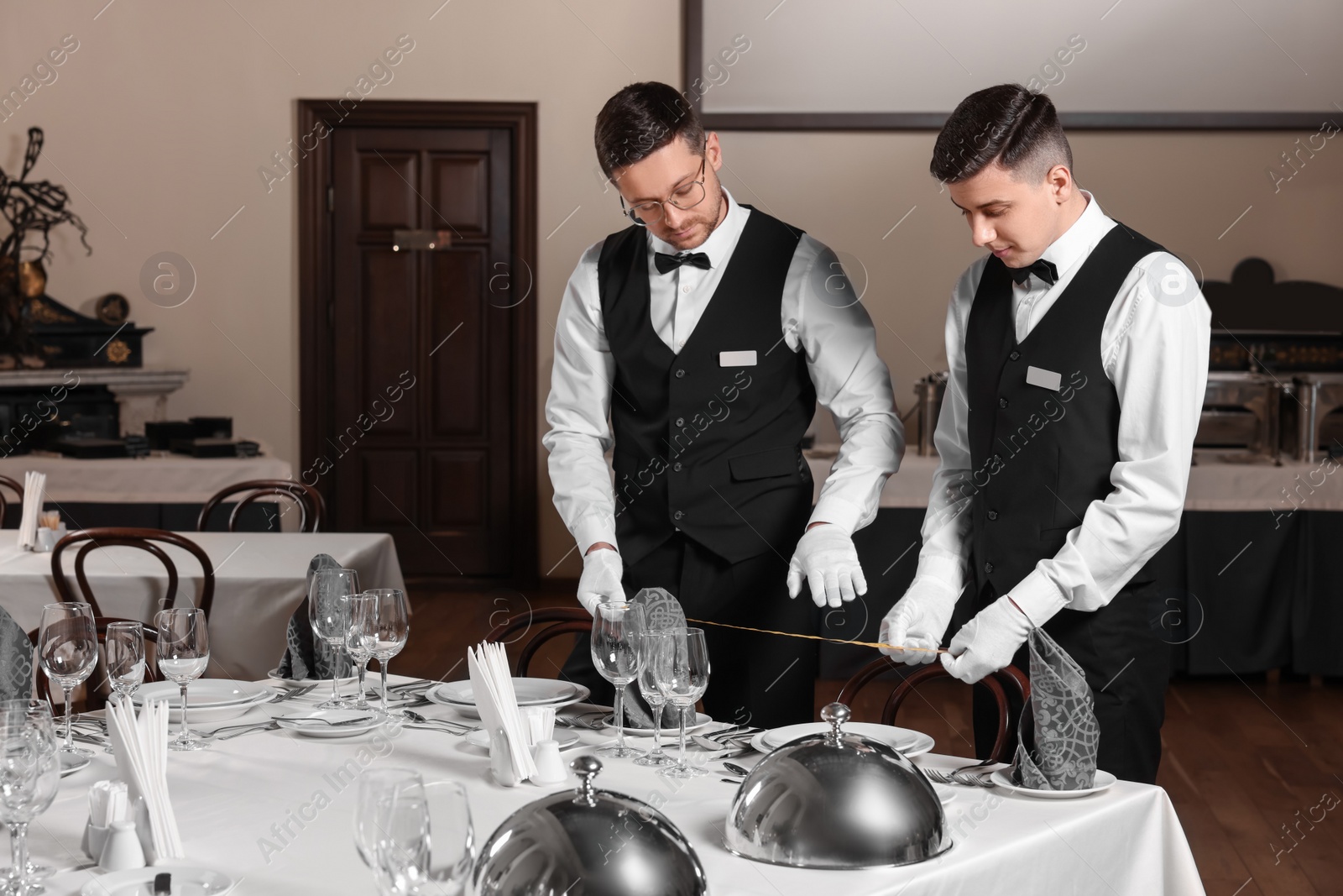 Photo of People setting table during professional butler courses in restaurant