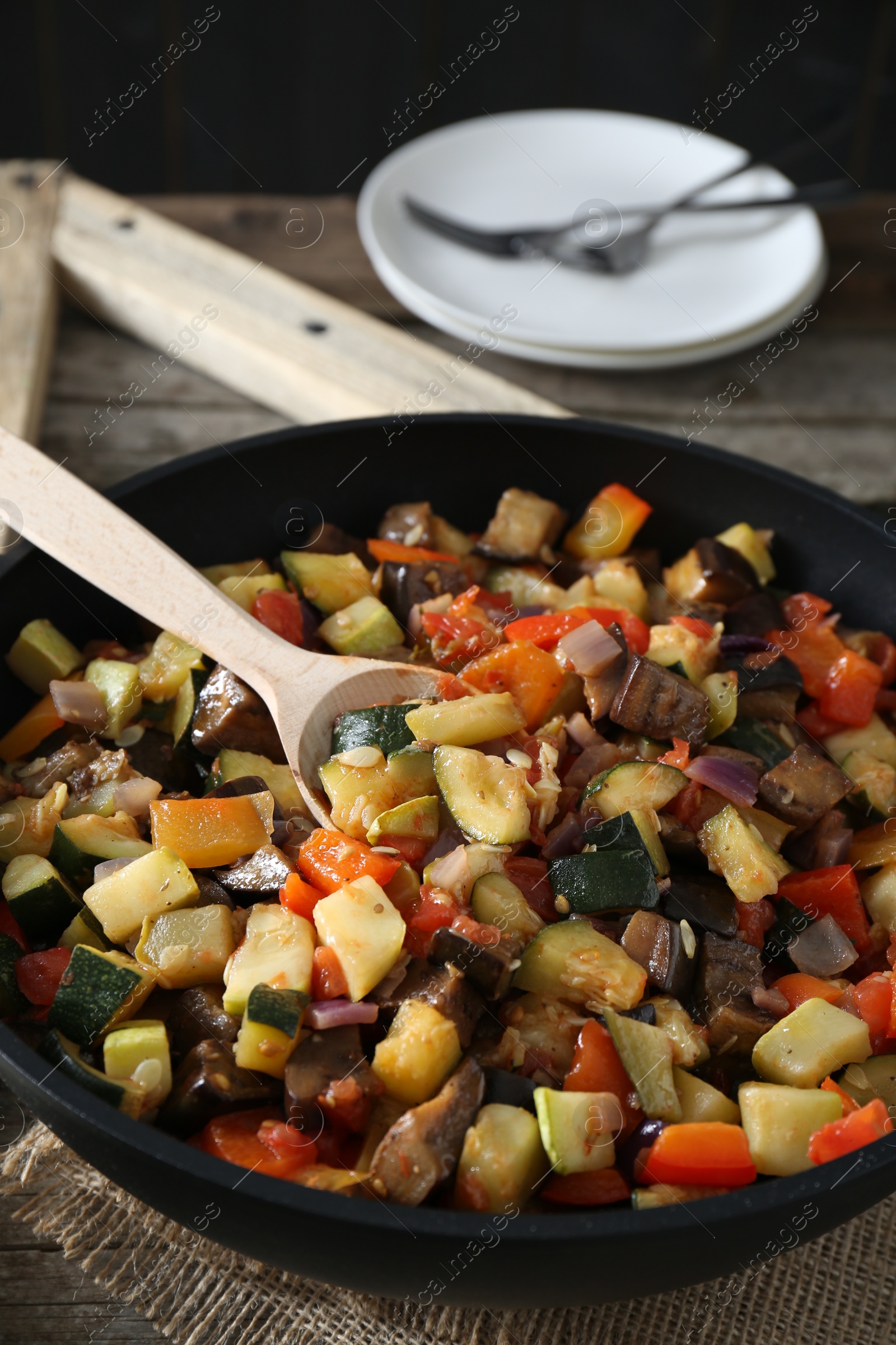 Photo of Delicious ratatouille and spoon in baking dish on table, closeup