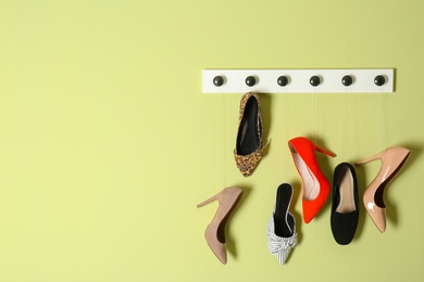 Photo of Different lady's shoes hanging on rack against color background, space for text