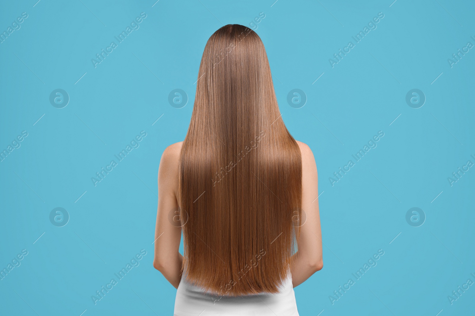 Photo of Woman with healthy hair on light blue background, back view