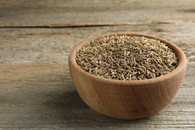 Photo of Bowl of caraway seeds on wooden table, closeup. Space for text