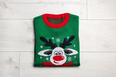 Folded warm Christmas sweater on wooden table, top view