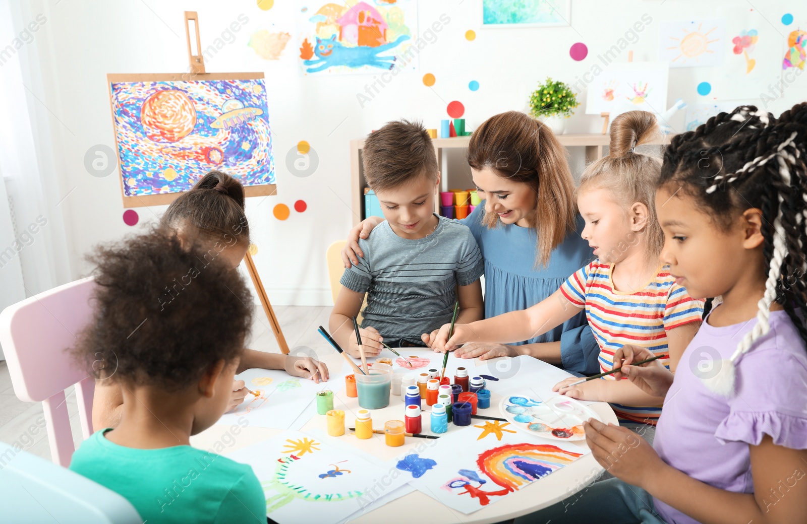 Photo of Children with female teacher at painting lesson indoors