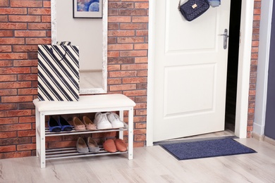 Photo of Hallway interior with shoe rack, mirror and mat near door