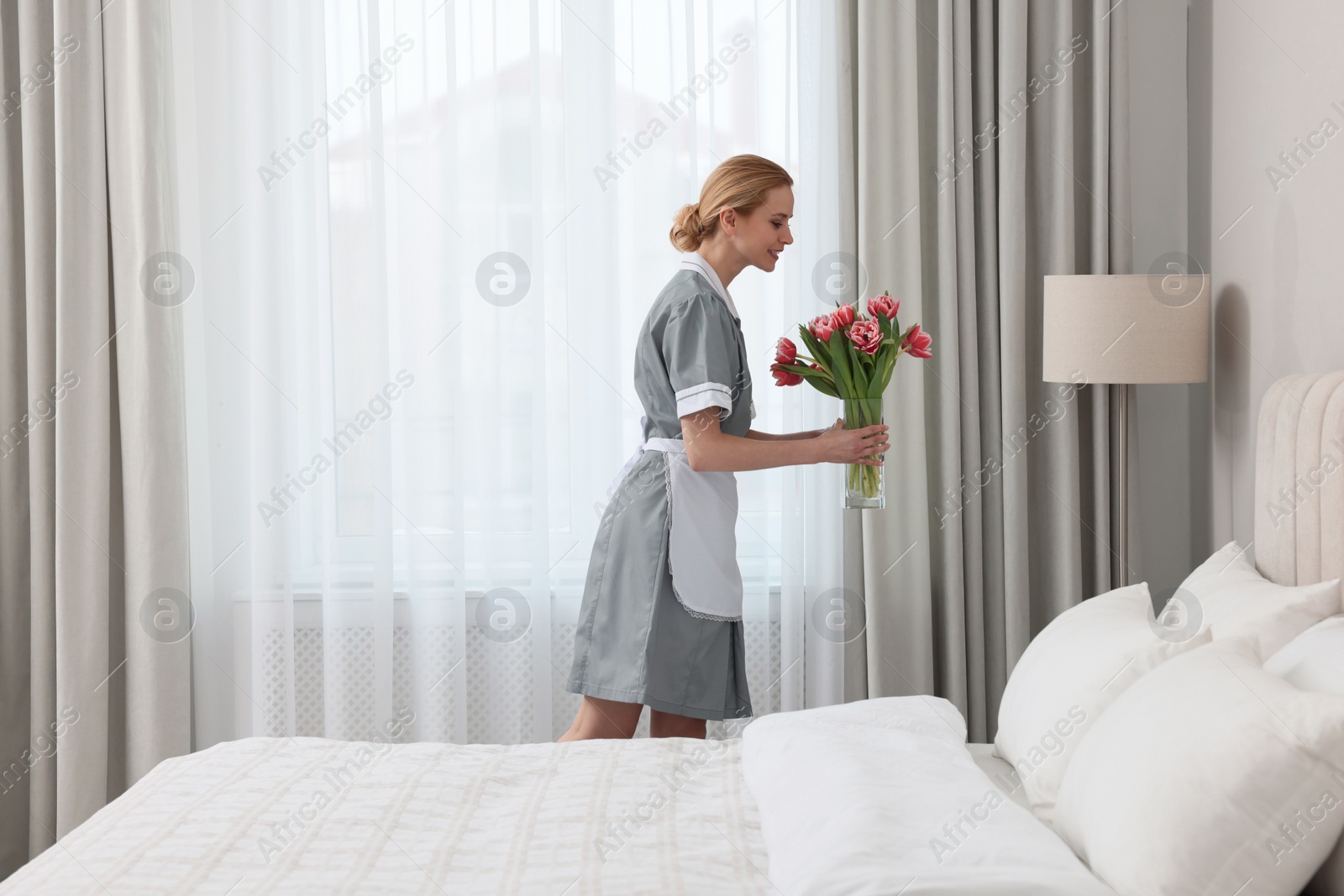 Photo of Chambermaid with fresh flowers in hotel bedroom