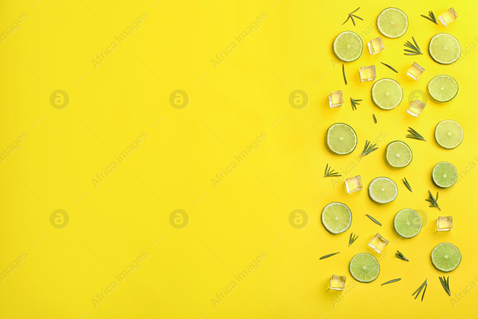 Photo of Lemonade layout with juicy lime slices, rosemary and ice cubes on yellow background, top view. Space for text