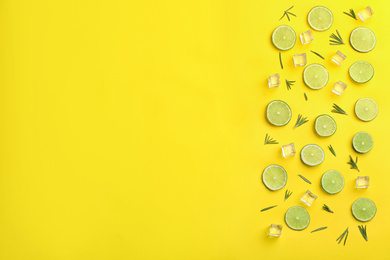 Photo of Lemonade layout with juicy lime slices, rosemary and ice cubes on yellow background, top view. Space for text
