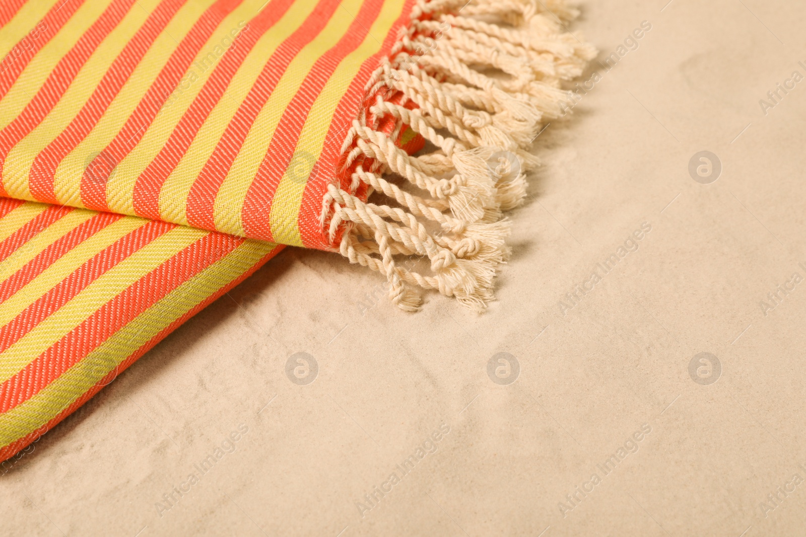 Photo of Striped soft beach towel on sand, closeup