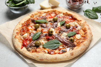 Photo of Tasty pizza with anchovies and ingredients on white table