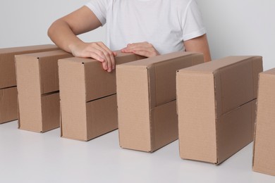 Photo of Woman folding cardboard boxes at white table, closeup. Production line