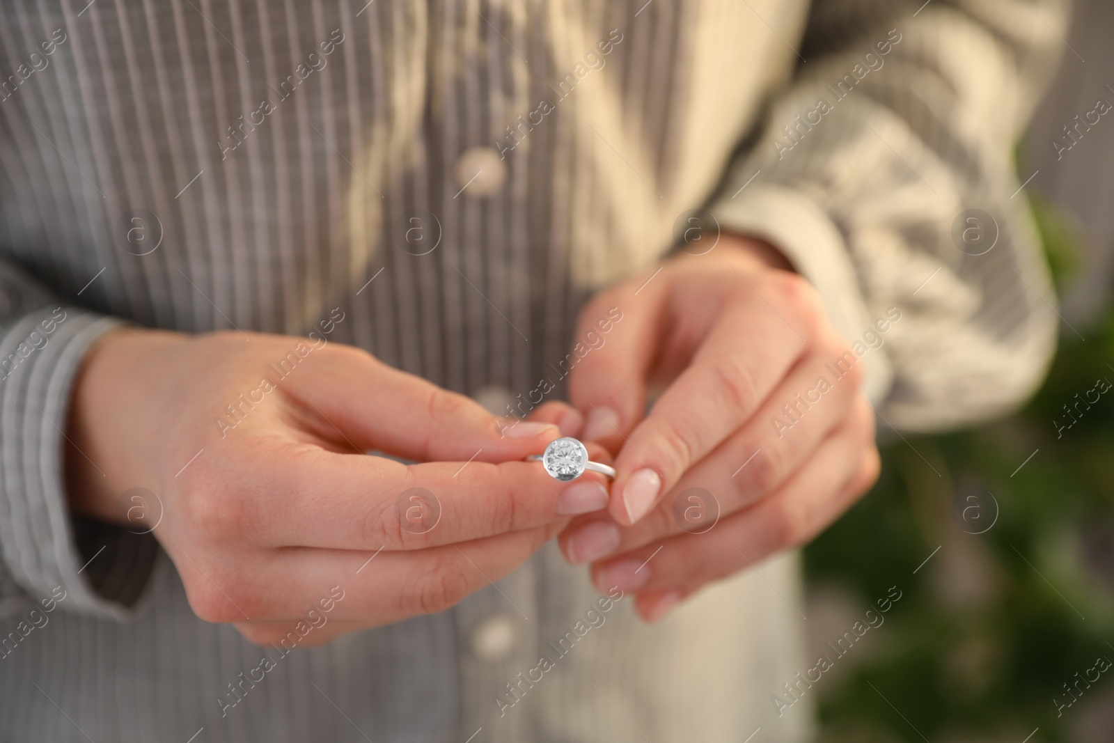 Photo of Woman holding wedding ring indoors, closeup. Divorce concept