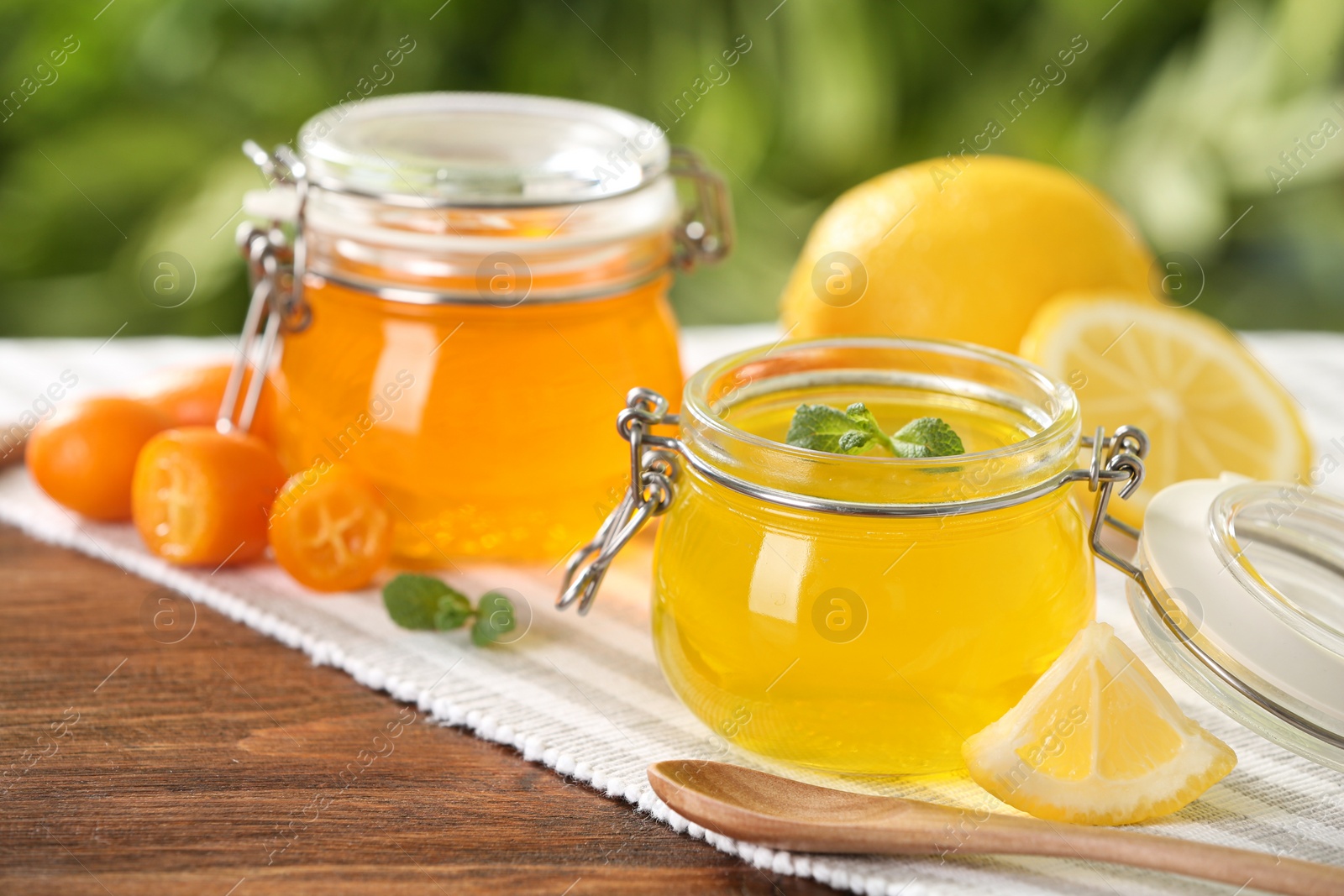 Photo of Glass jars of fruit jelly desserts on wooden table, space for text