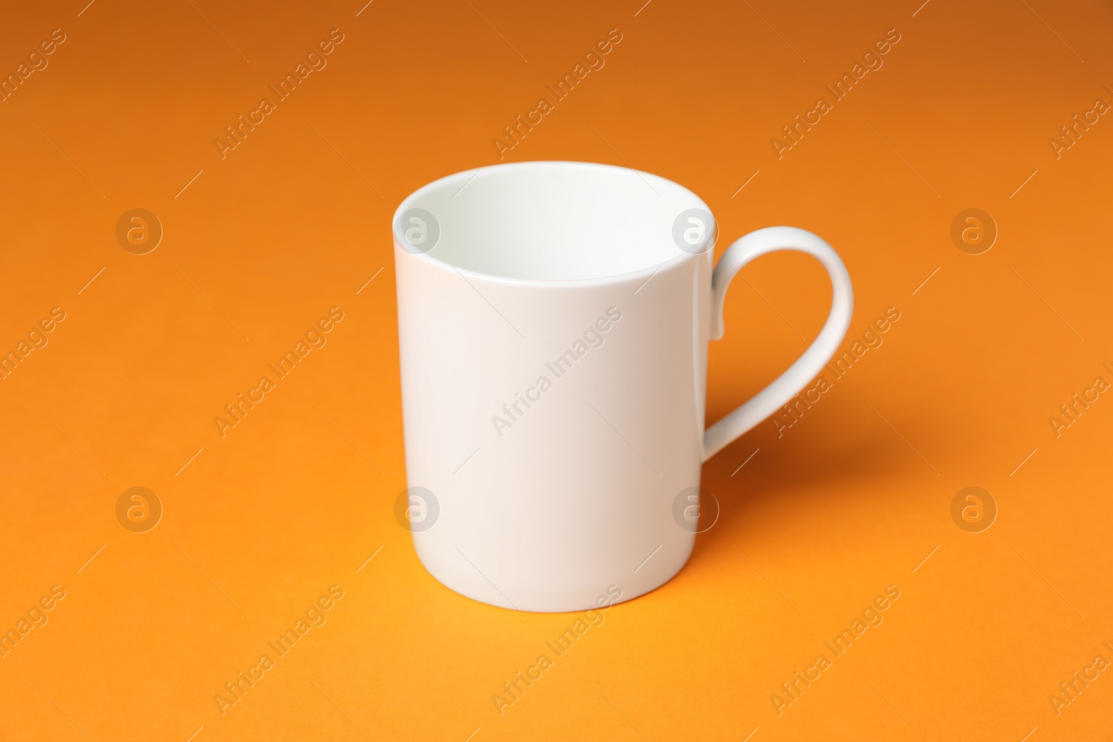 One white ceramic mug on orange background Photo of One white ceramic mug on orange background