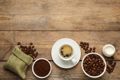 Flat lay composition with coffee grounds and roasted beans on wooden table, space for text