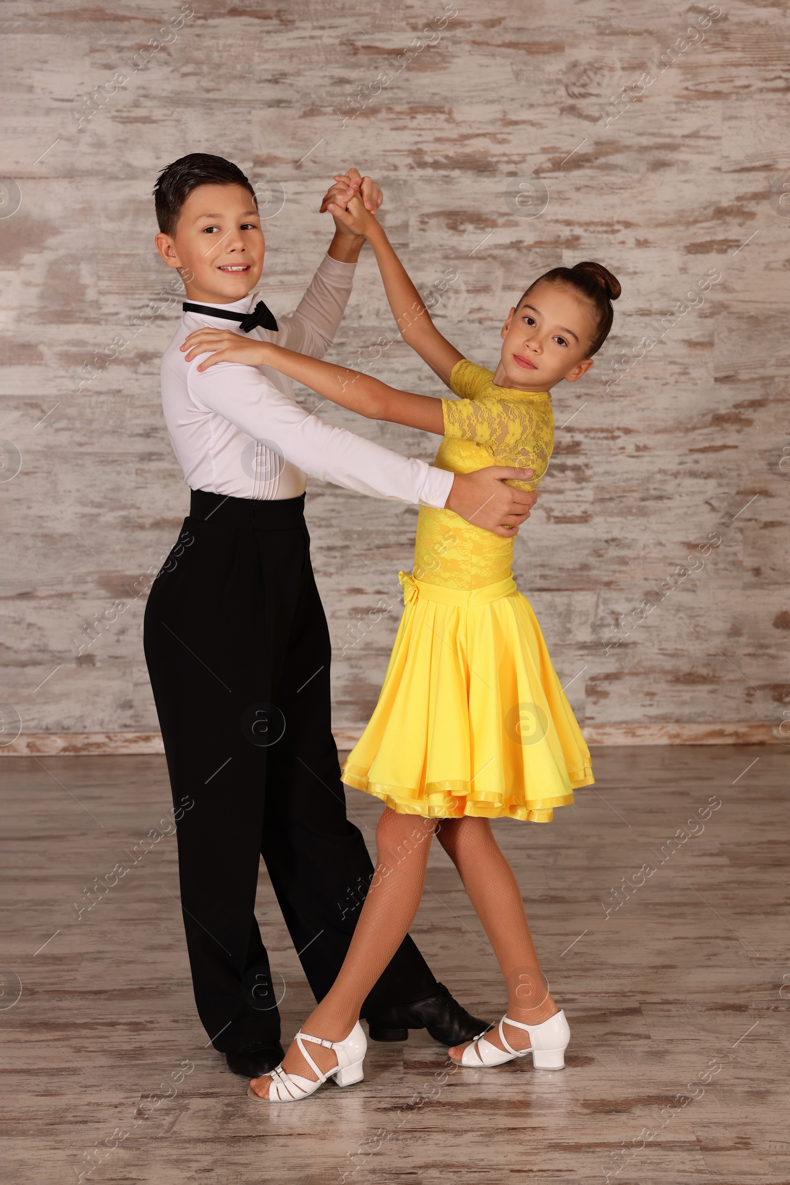 Photo of Beautifully dressed couple of kids dancing together in studio