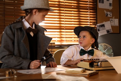 Photo of Cute little detectives at table in office