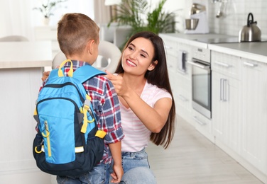 Happy mother and little child with backpack ready for school in kitchen