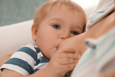 Woman breastfeeding her little baby at home, closeup