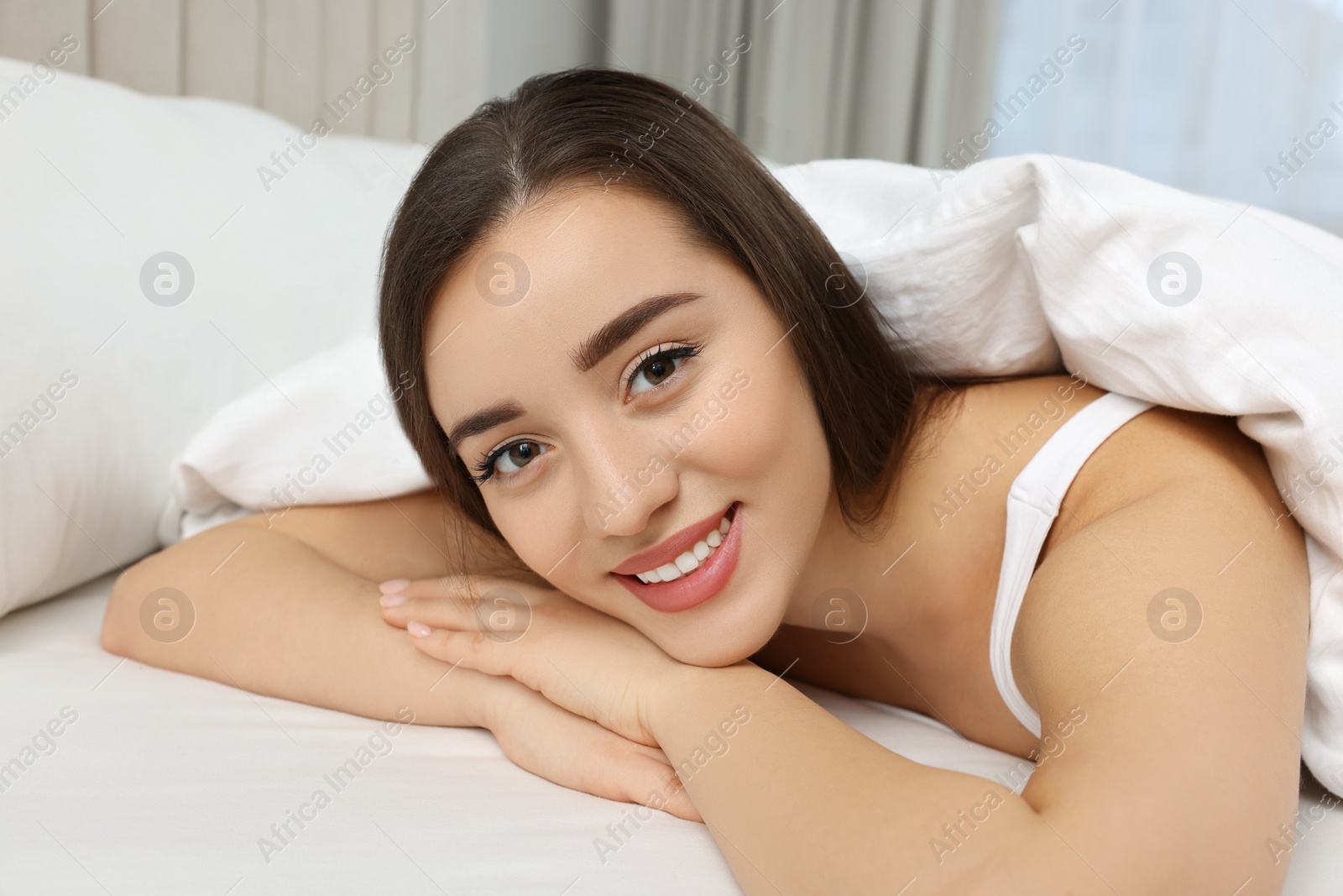 Photo of Beautiful young woman lying in bed at home