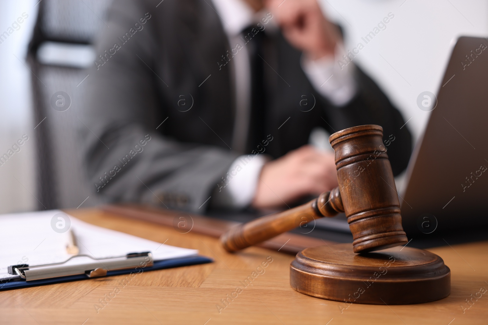 Photo of Notary working with laptop at wooden table, focus on gavel