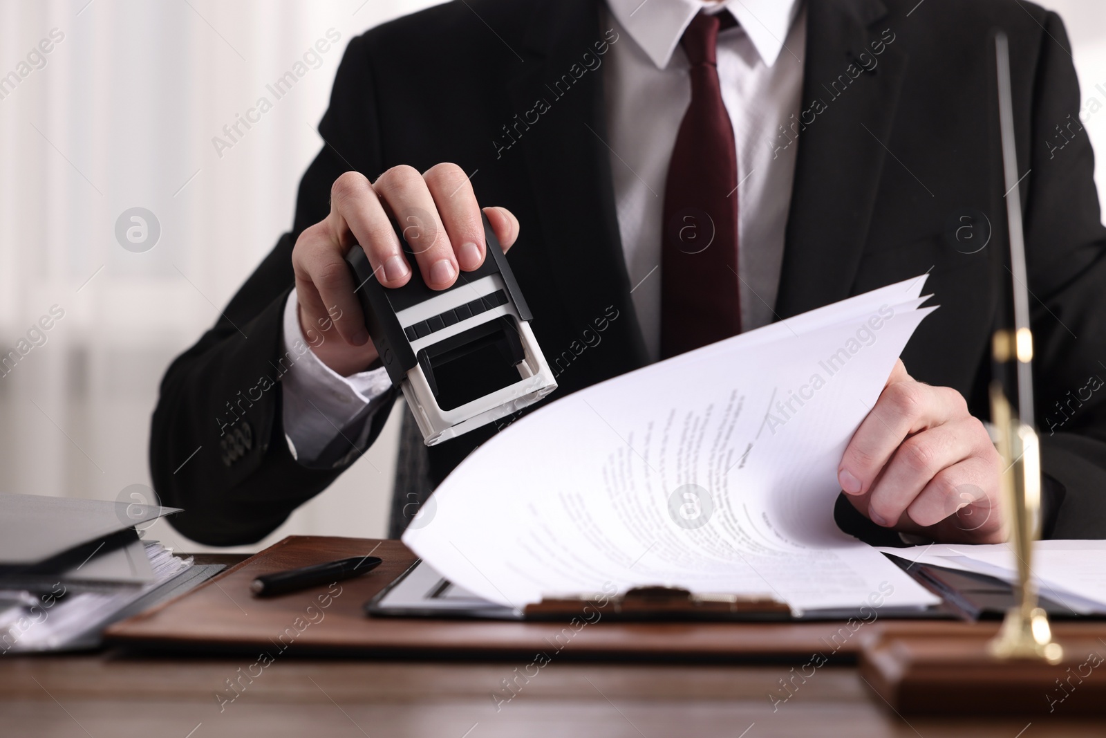 Photo of Notary stamping document at table in office, closeup