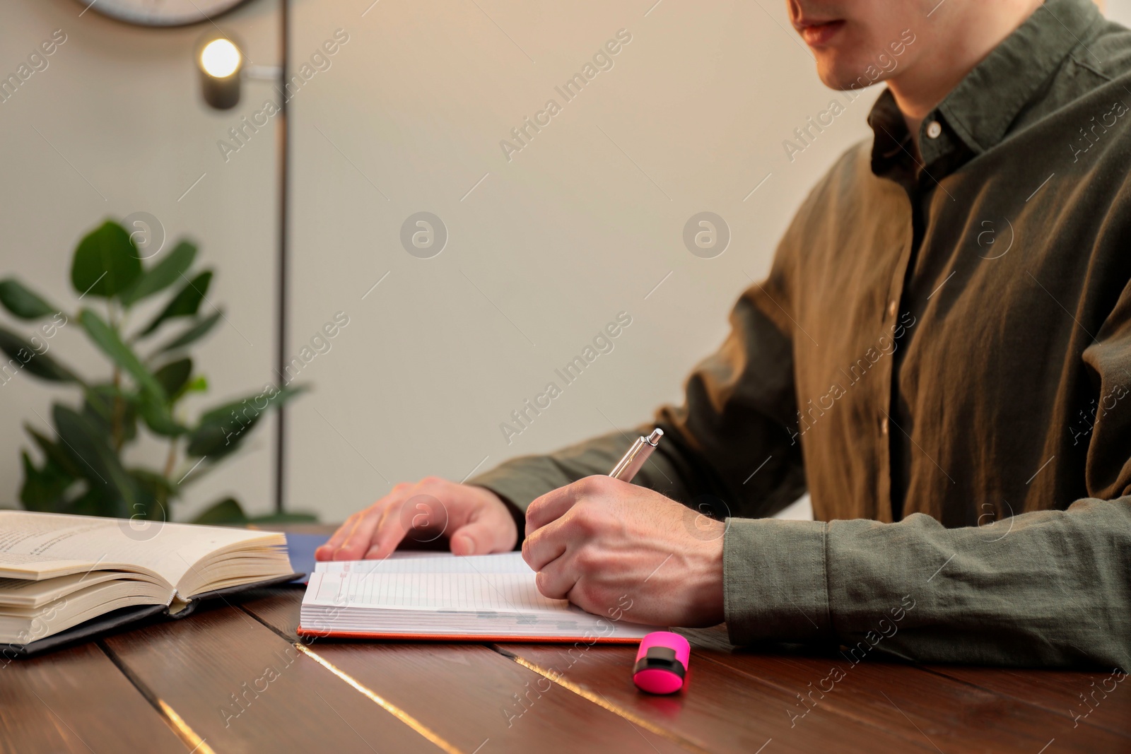 Photo of Man taking notes at wooden table in office, closeup. Space for text