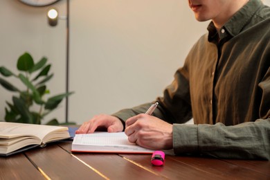 Photo of Man taking notes at wooden table in office, closeup. Space for text