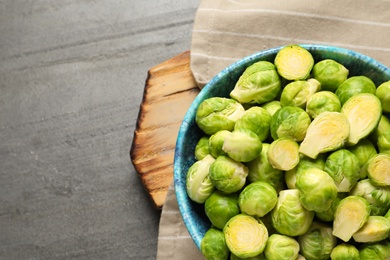 Photo of Bowl with fresh Brussels sprouts on grey table, top view. Space for text