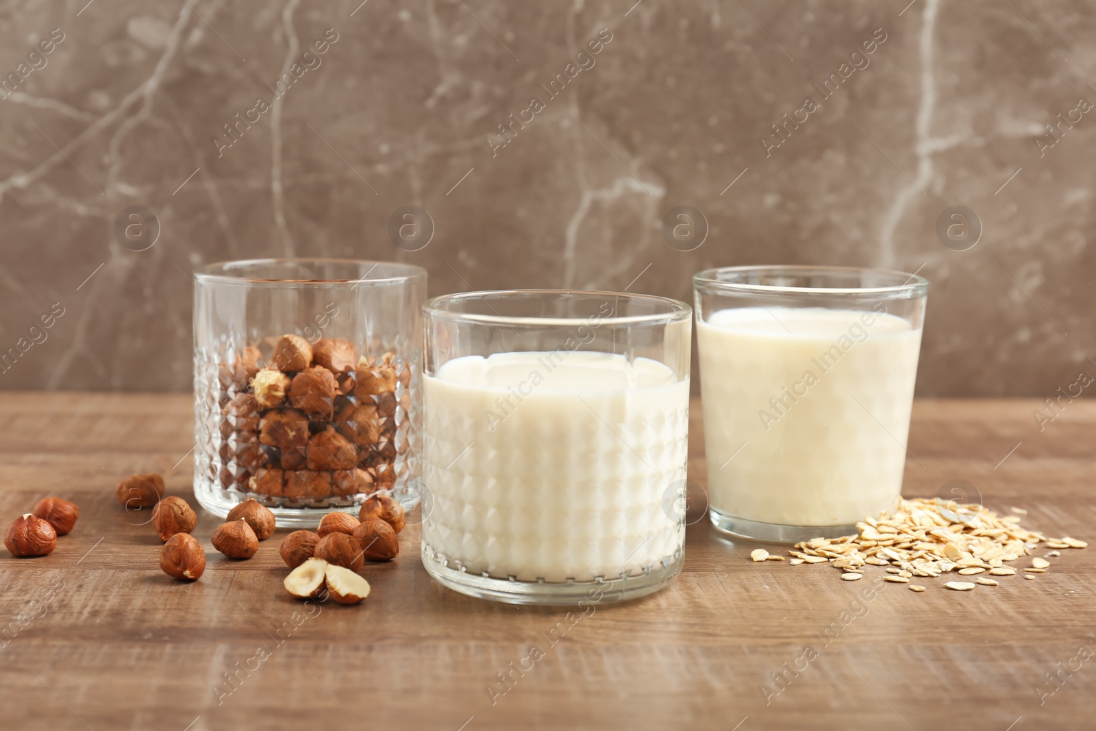 Photo of Glasses with hazelnut and oat milk on wooden table