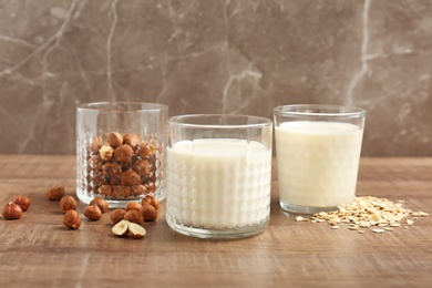Photo of Glasses with hazelnut and oat milk on wooden table
