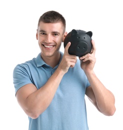 Handsome young man with piggy bank on white background