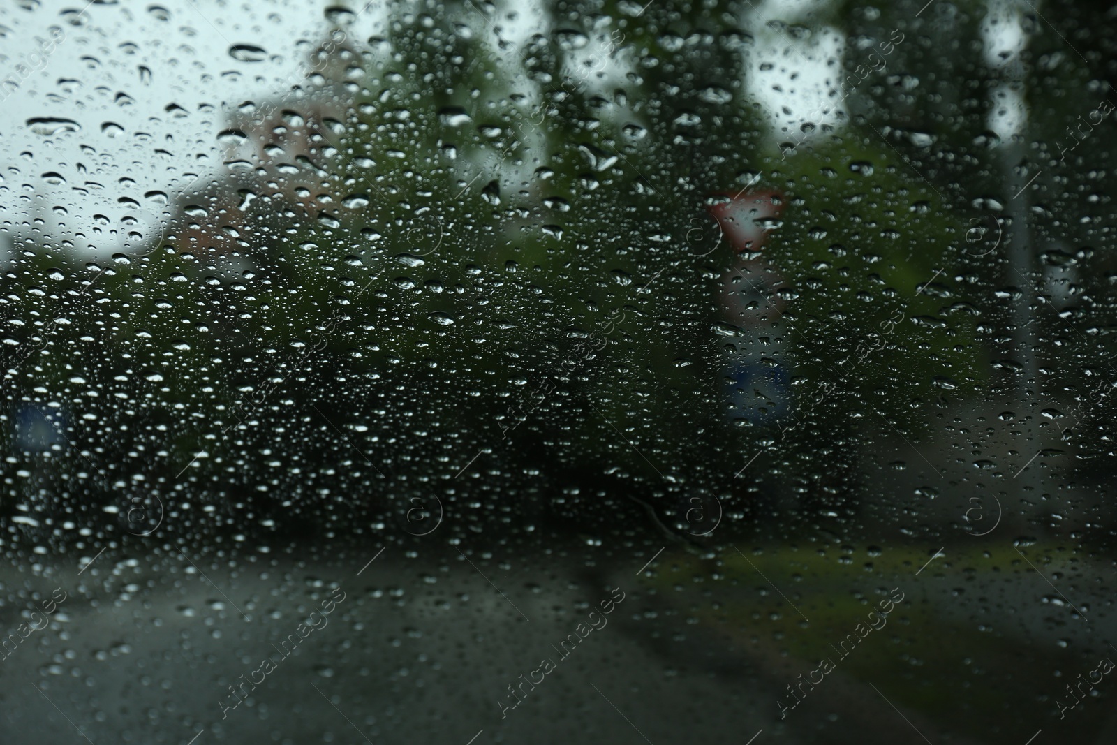 Photo of Blurred view of road through wet car window. Rainy weather