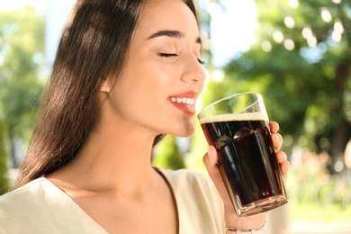 Photo of Beautiful woman with cold kvass outdoors, closeup. Traditional Russian summer drink