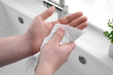 Photo of Man wiping hands with paper towel near sink, closeup