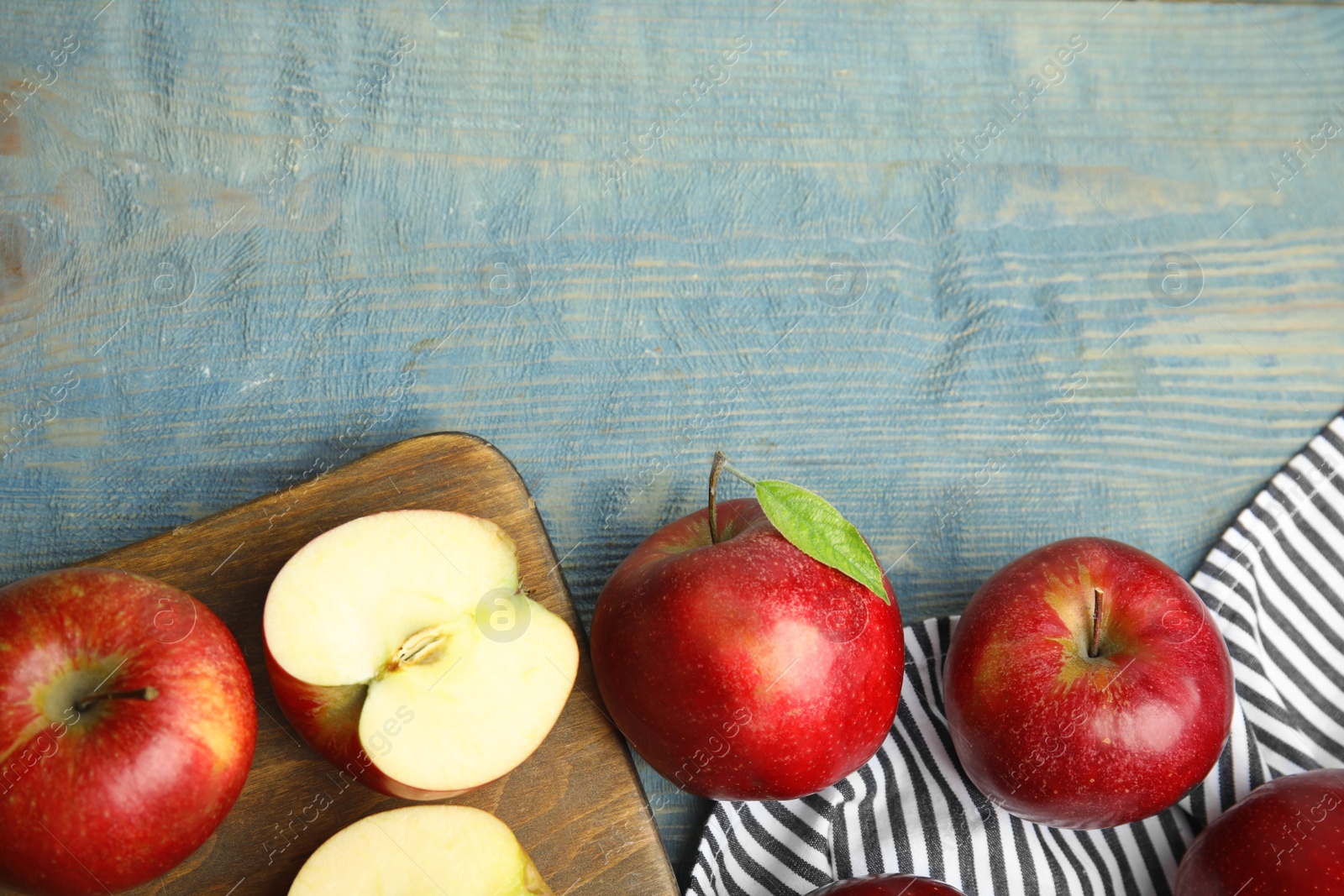 Photo of Ripe juicy red apples on blue wooden background, flat lay. Space for text