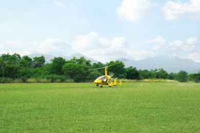 Photo of Yellow rotorcraft on grass near trees outdoors