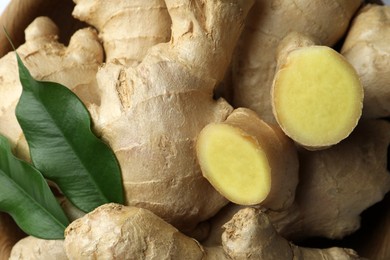 Photo of Fresh ginger with leaves in bowl, top view