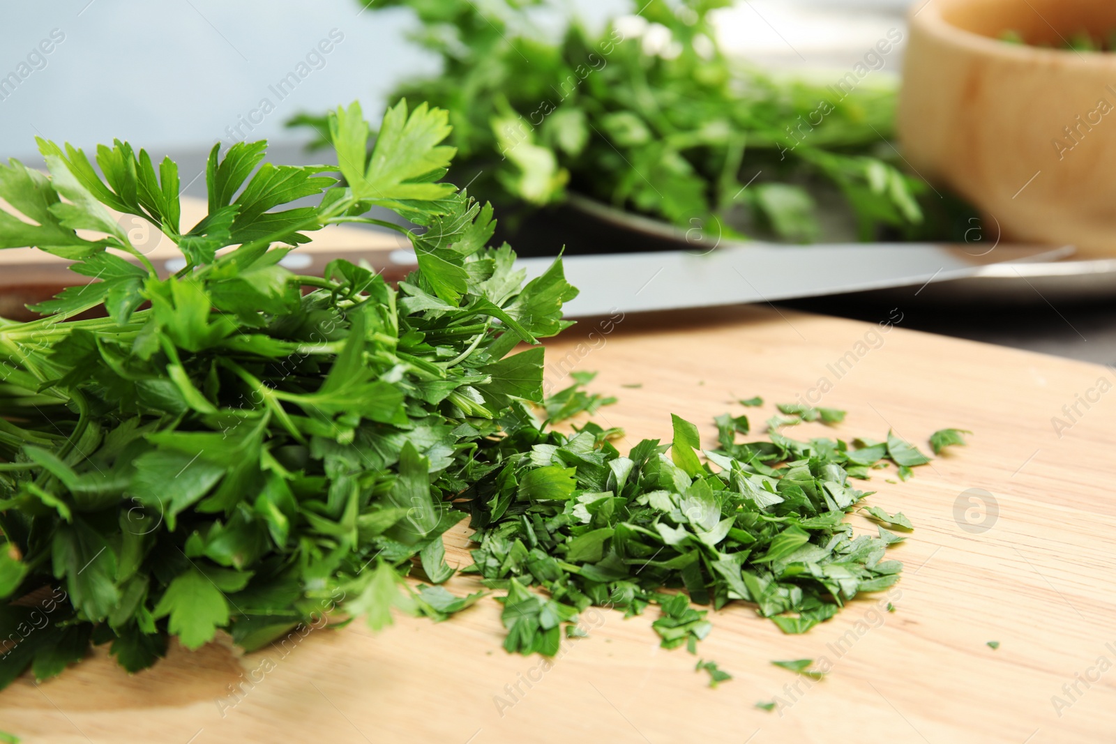 Photo of Wooden board with chopped parsley on table, closeup