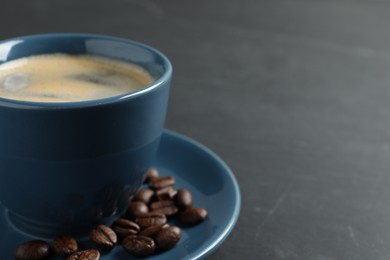 Cup of aromatic coffee and beans on grey table, closeup. Space for text