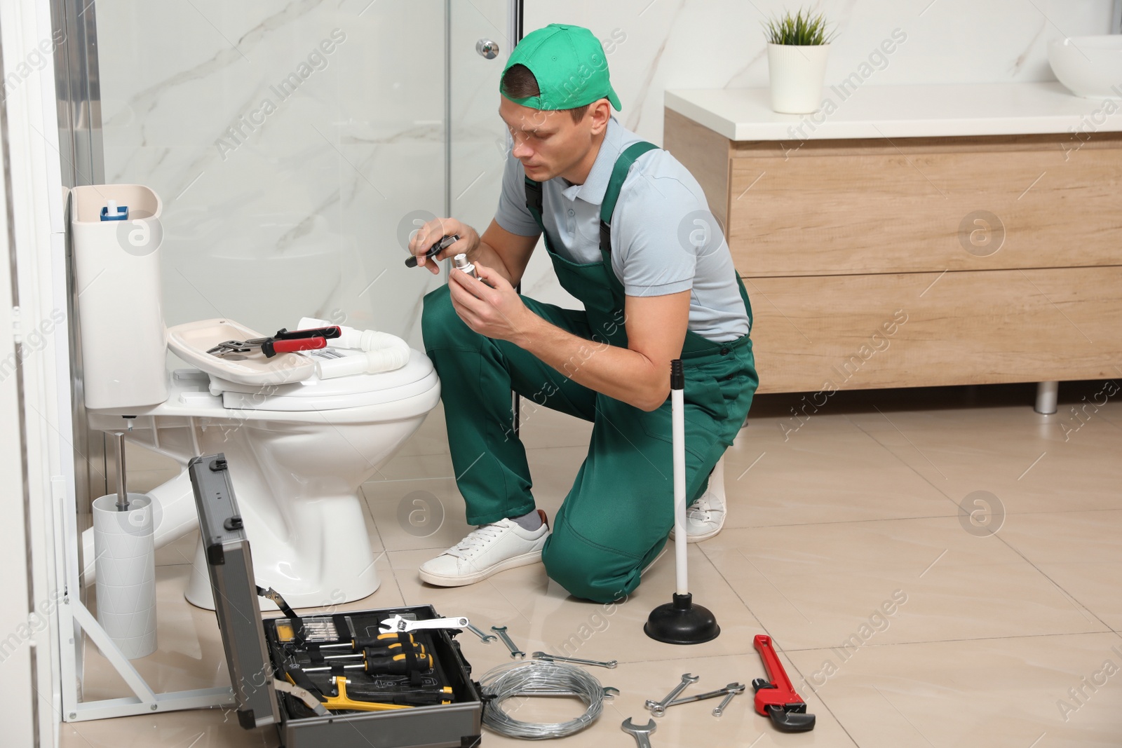 Photo of Professional plumber repairing toilet tank in bathroom