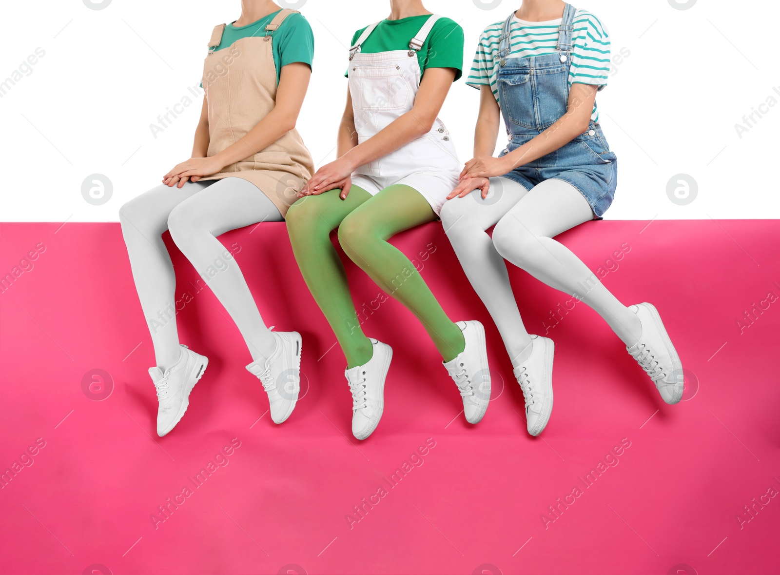 Photo of Group of women wearing colorful tights and stylish shoes sitting on color background, closeup