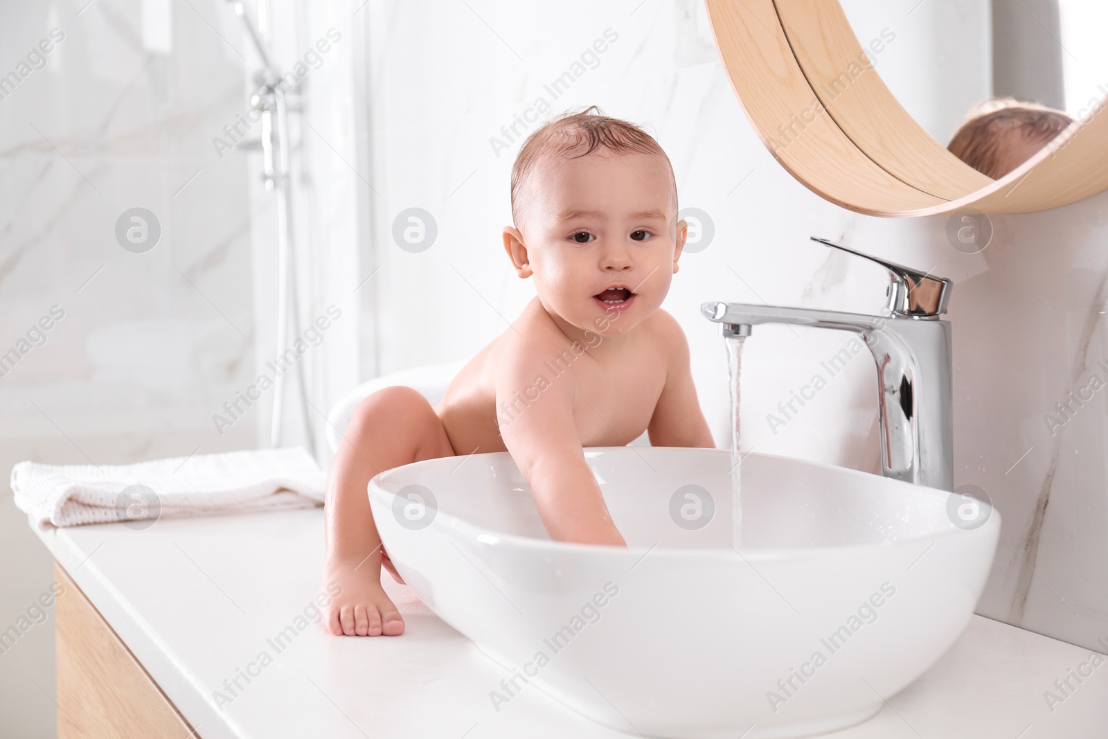 Photo of Cute little baby playing in bathroom at home