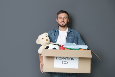 Photo of Young man holding box with donations on grey background