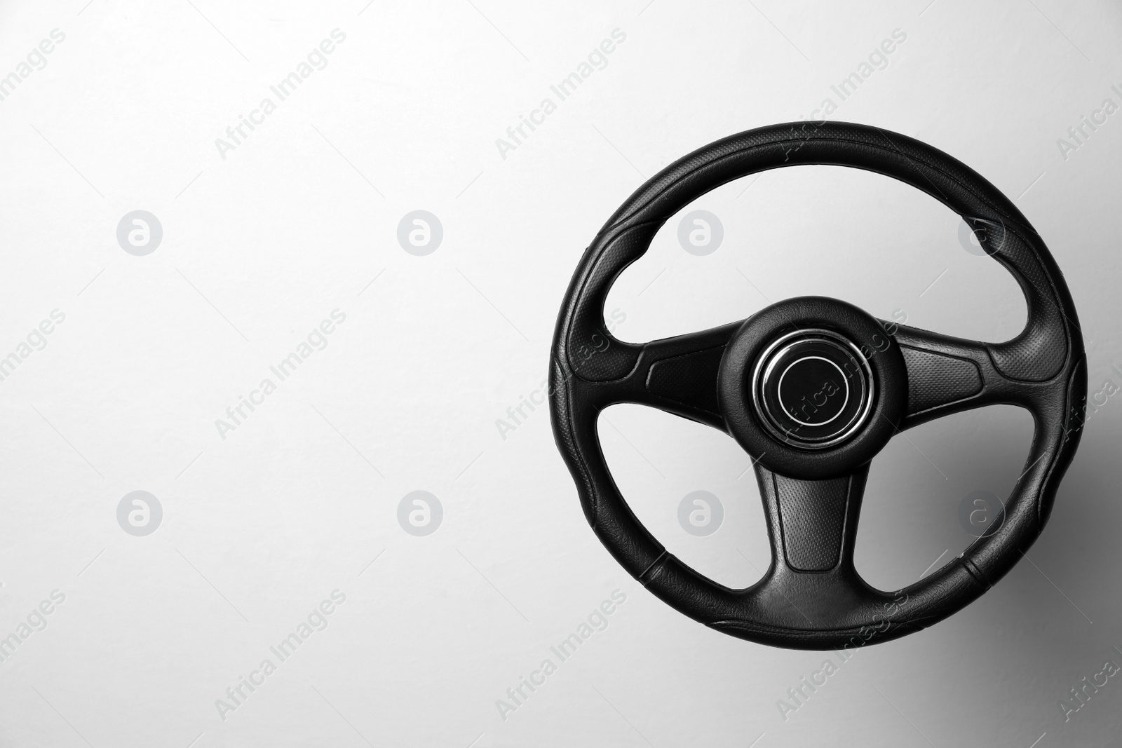 Photo of New black steering wheel on white background, space for text