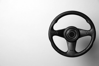 Photo of New black steering wheel on white background, space for text