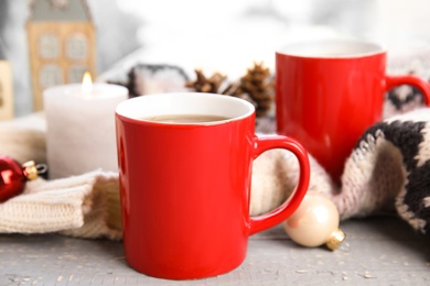 Photo of Cups of hot winter drink with scarf on window sill indoors