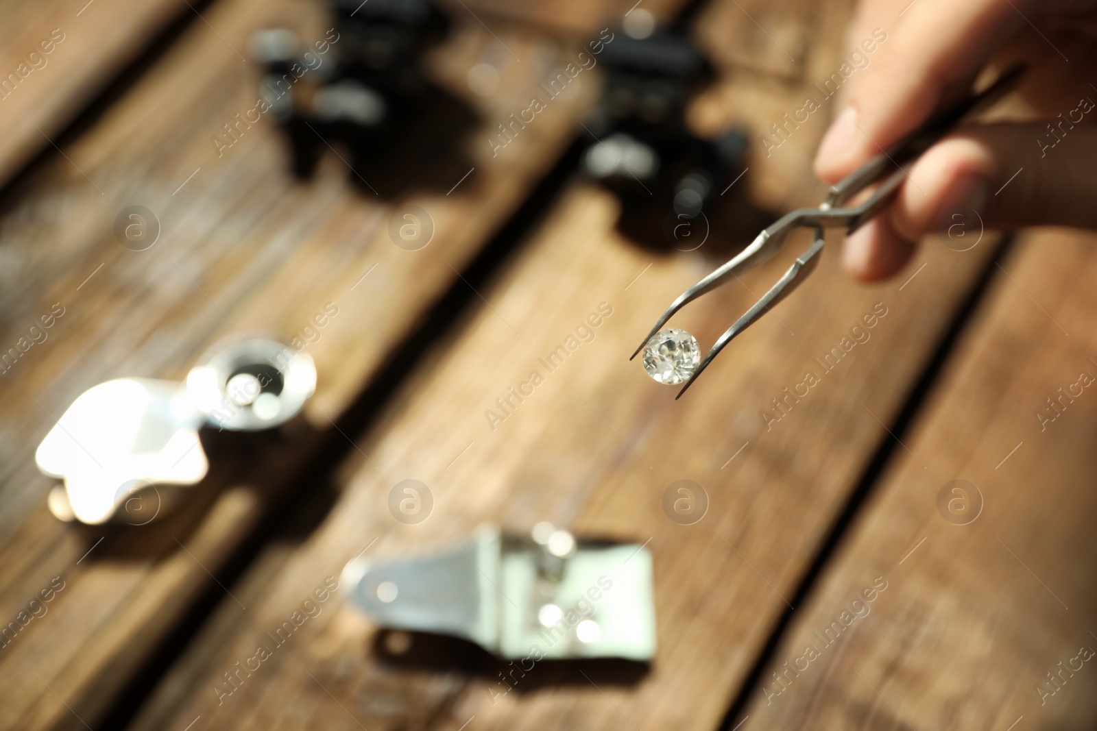 Photo of Male jeweler evaluating precious gemstone at table in workshop, closeup