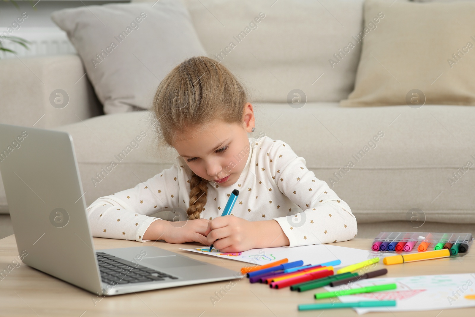 Photo of Little girl drawing with felt-tip pen following online course at home. Time for hobby